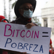A man holds a sign that reads in Spanish: “bitcoin equals poverty,” in San Salvador, El Salvador on Sept. 1, 2021.